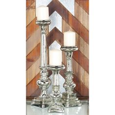 two silver candles sitting on top of a white table next to a wooden paneled wall