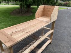 a large wooden bench sitting on top of a sidewalk next to a green grass covered park