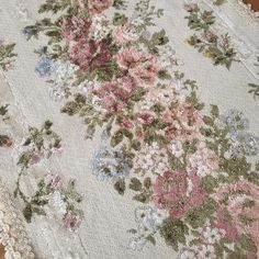 an old rug with flowers and lace on the bottom is laying on a wooden floor