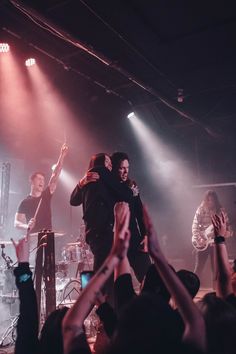 two men hugging each other on stage with their arms in the air and people clapping