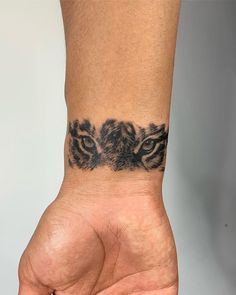 a person's hand with a tattoo on the wrist that has two tigers on it