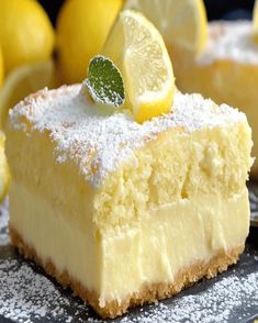 a slice of lemon cake with powdered sugar on top and fresh lemons in the background