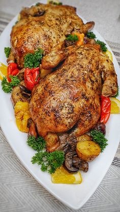 two whole chickens on a white plate with vegetables