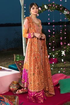 a woman in an orange and pink dress standing on a bed of flowers at night