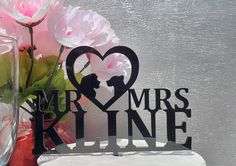 a vase filled with pink flowers next to a metal mr and mrs sign