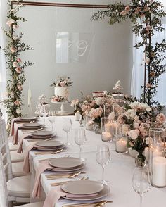 the table is set with white and pink flowers, candles, and place settings for dinner