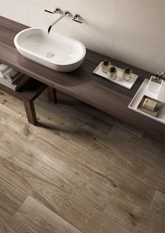 a white sink sitting on top of a wooden counter next to a bowl shaped sink