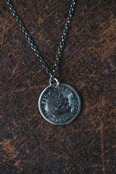 a silver coin is on a chain that has been placed on top of a brown surface