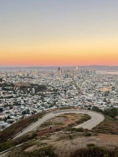 a view of a city from the top of a hill with a road going through it