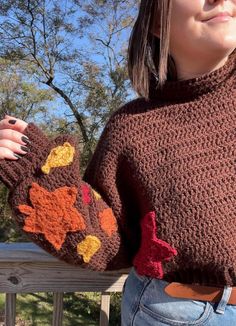 a woman wearing a brown knitted sweater with an orange and yellow flower on it