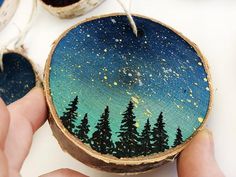 a person holding a piece of wood that has been painted with trees and stars on it