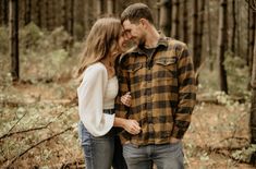 a man and woman standing next to each other in the woods