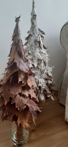 a glass vase filled with leaves next to a small tree on top of a wooden table