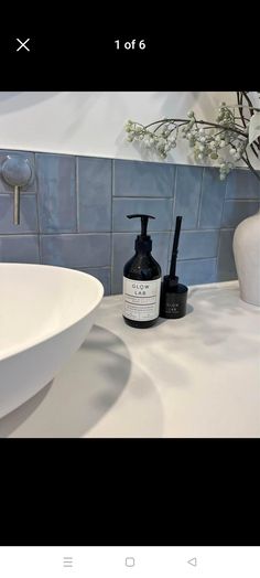 a white sink sitting under a bathroom mirror next to a faucet and soap dispenser