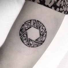 a black and white photo taken from the side of a woman's leg with a circular tattoo on it