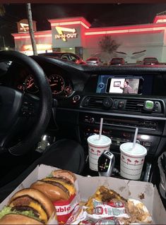 the interior of a car with food and drinks in front of it, including burgers