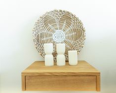 two white vases sitting on top of a wooden table next to a wicker fan