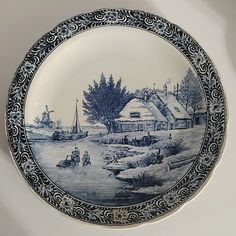 a blue and white plate with a village scene on it