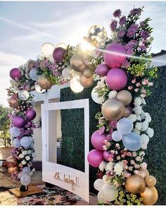 a decorated entrance with balloons and flowers on the outside, in front of a mirror