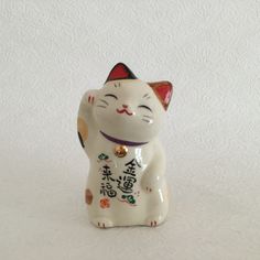 a white cat figurine with chinese writing on it's chest and ears