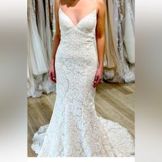 a woman in a white wedding dress standing in front of a rack of gowns