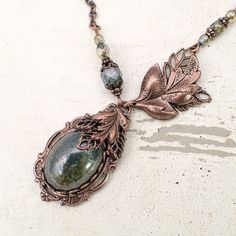 Rustic green Czech glass wrapped with delicately detailed antique copper leaves. --------------------------------------------------------------------------------------------- Dimensions and details - Focal cabochon measures 18x13mm - The drop of the entire pendant (top of setting to bottom of setting) is approximately 1 and 3/8 inches (35mm) - Central set stone is Czech glass - Filigree, leaves, and settings are USA-made antiqued copper-plated brass, lead-free and nickel free - Chain and findings are antiqued copper-plated brass, lead-free and nickel-free --------------------------------------------------------------------------------------------- Sizing Length:  - You may choose your desired length from the drop-down menu. This will be the length of your necklace when clasped.  - Please n Victorian Style Jewelry, Vintage Jewelry Diy, Cabochon Necklace, Electroformed Jewelry, Vintage Style Jewellery, Victorian Jewelry, Vintage Jewels, Copper Earrings, Crystal Pearls