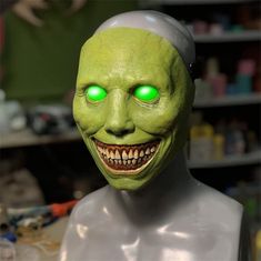 a creepy mask with glowing green eyes on a mannequin head