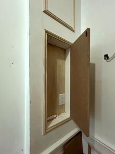 an open door in the corner of a room with white walls and wood flooring