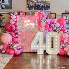 the number forty is surrounded by balloons and streamers in front of a photo frame