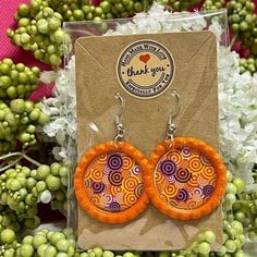 a pair of orange and purple earrings sitting on top of a card