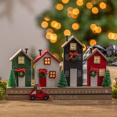 three small houses with christmas decorations on them and a red car parked in the foreground