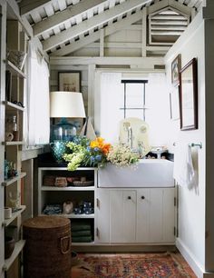 a kitchen with white cabinets and flowers on the counter top in front of a window