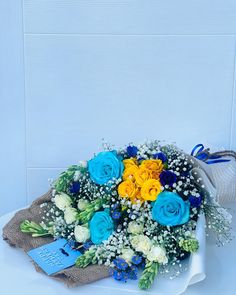 a bouquet of blue, yellow and white flowers sitting on top of a cloth bag