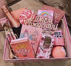 a pink box filled with lots of different types of items and candy canes on top of a couch