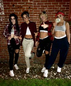 three women standing next to each other in front of a brick wall with money sticking out of their mouths