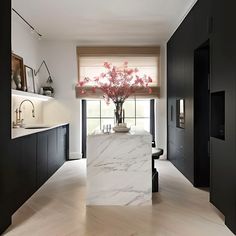 a kitchen with black cabinets and white marble counter tops, along with an island in the middle