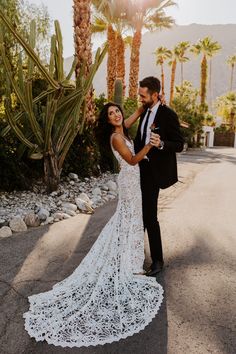 a bride and groom standing in front of palm trees