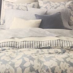 an unmade bed with blue and white sheets