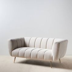 a white couch sitting on top of a hard wood floor next to a gray wall