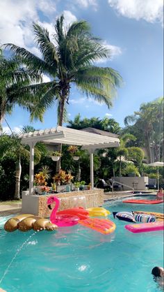 an outdoor pool with inflatable toys and palm trees