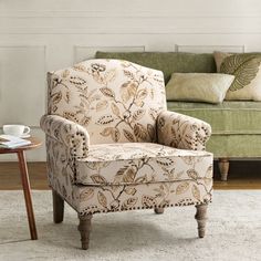 a living room with a green couch, chair and coffee cup on the table in front of it