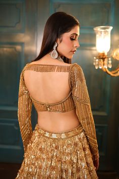 Ombre gold and silver bridal lehenga embellished with sequin, crystals, beads, cutdana embroidery, and a matching full-sleeved blouse in gold. The lehenga comes with a shaded embroidered cutwork dupatta.DELIVERY TIMEPlease allow 8-12 weeks for your outfit to arrive.FABRIC DETAILSNetProfessional cleaning only. Golden Lehenga Blouse Designs, Blouse Designs Full Sleeves, Silver Bridal Lehenga, Lehenga Blouse Designs Back, Sequin Blouse Designs, Golden Saree Blouse Designs, Lehenga Gold, Silver Lehenga, Golden Lehenga