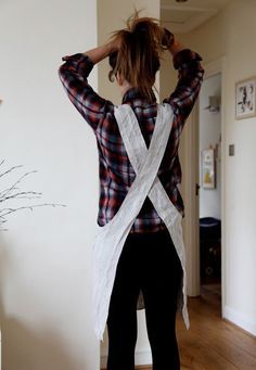 a woman standing in front of a white wall with her back turned to the camera