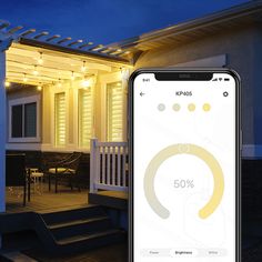 an iphone displaying the home security app in front of a house with lights on it