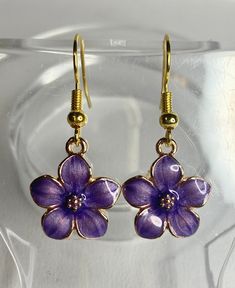 These little purple flowers are just the cutest things I've ever seen! They go great with just about anything, whether it's a pair of jeans or a date night to a movie. Made with gold plated metal and enamel, hanging from stainless steel ear wires.These measure 1.25" (Approximate measurement, includes ear wire)Any metals used in jewelry are Zinc alloy (lead and nickel free), tarnish resistant (except for copper, which will change color(patina) over time). Metals are either bare copper, silver-ton Enamel Jewelry For Spring Gifts, Spring Enamel Jewelry For Gifts, Spring Enamel Jewelry As Gift, Spring Gift Enamel Jewelry, Enamel Flower Earrings With Flower Charm, Enamel Flower Charm Earrings, Trendy Purple Flower Earrings For Gift, Trendy Purple Jewelry For Spring, Purple Metal Earrings As Gift