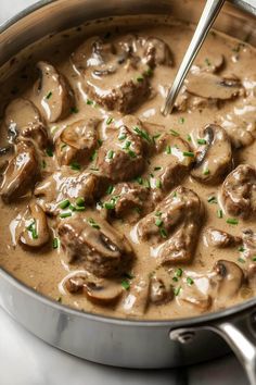 a pan filled with meat and mushrooms covered in gravy