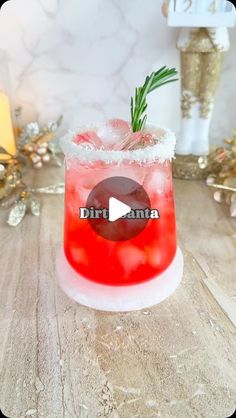 a red drink sitting on top of a wooden table next to candles and christmas decorations