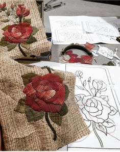 two pieces of fabric with red flowers on them sitting next to some scissors and paper