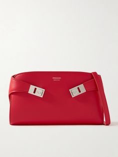 Ferragamo's shoulder bag is named 'Hug' after the 'Gancio' clasps that frame the sides. It has been crafted in Italy from red leather with a detachable strap so you can wear it as a clutch and is branded with a small foil logo. The interior will fit your mints, cardholder and phone, plus a lipstick for touching up. Embellished Bags, Flat Dress Shoes, Gucci Eyewear, Raffia Bag, Salvatore Ferragamo, Leather Crossbody Bag, Fashion Bracelets, Fashion Watches, Evening Bags