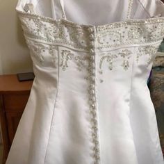 a white dress with beading on the shoulders and neckline, sitting on a table